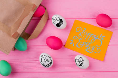 Happy Easter lettering on yellow card. Various Easter eggs and kraft paper packet. Easter holidays art.の写真素材