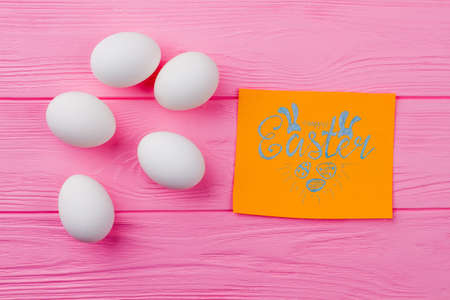 Happy Easter concept on wooden background. Flat lay white Easter eggs and greeting card. Ideas for easy Easter congratulation.の写真素材