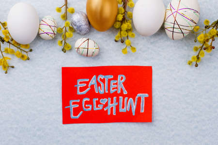 Easter egg hunt. Golden egg among white eggs decorated with pussy willow. Easter egg hunt party.の写真素材