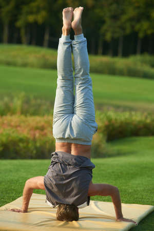 Yoga headstand in the park. Standing upside down on the head.の写真素材
