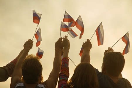 Russian peoples hands with flags. Bright evening sky at the down.の写真素材