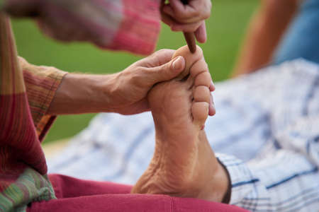 Thai foot massage training course. Wooden stick touching foot finger, close up.の写真素材