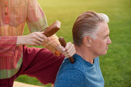 Thai massage by wood hammer for treat. Hammering pounds came down on mans back.