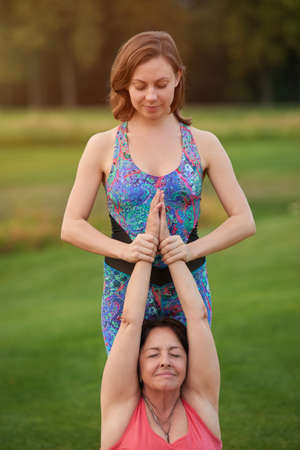 Thai massage exercise, folding hands up. Portrait of two women doing thai massage.の写真素材