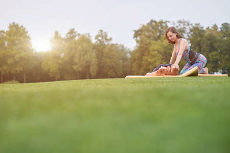 Yoga exercise in the summer. Distant plan of two women doing thai massage on the grass.の写真素材