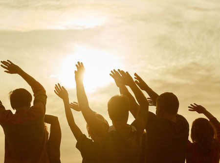 Silhouettes of happy people with hands up. Warming-up before sport exercises.の写真素材