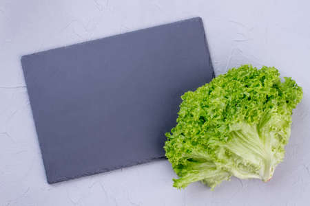 Fresh lettuce and square slate. Fresh lettuce salad and empty slate, top view. Culinary, cuisine, healthy food.の写真素材