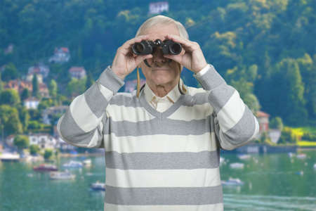 Portrait of senior with binoculars. Resort at vacation background.の写真素材
