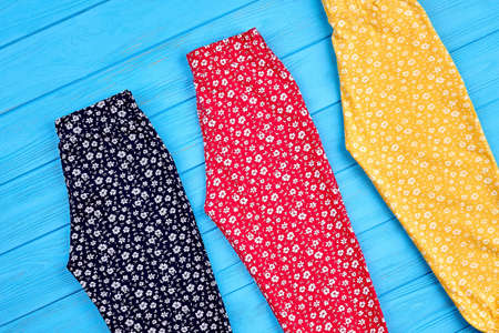 Baby girl colorful trousers. Collection of colored pants for little girl, wooden background. Trendy apparel for kids.の写真素材