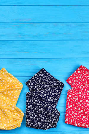 Baby leggings with pattern of flowers. Vertical image of cotton baby-girls pants on colored wooden...