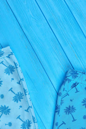 Baby summer apparel, copy space. Dainty design newborn clothes on blue wooden background, top view.
