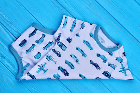 Baby boy natural bodysuit close up. Transport print baby romper on wooden background. Newborn boy summer outfit.の写真素材