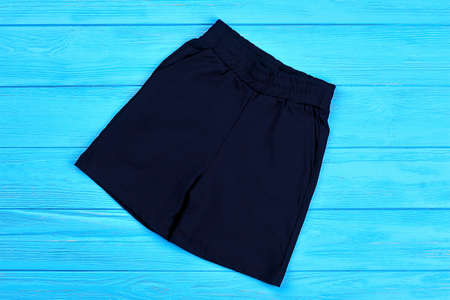 Dark blue cotton shorts for baby-boy. Textile short pants for little boys on blue wooden background. Trendy children shorts for casual wear.の写真素材