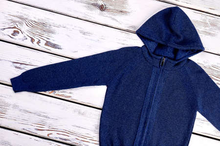 Top view of hooded cardigan for childrens. Knitted pullover with hoodie for boys on vintage wooden background.の写真素材