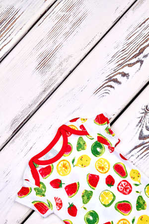 Infant kids brand patterned clothes. Baby girl or boy beautiful organic romper on old wooden background, copy space.の写真素材