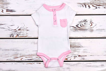 Newborn girl cute organic bodysuit. Infant girl high quality summer romper on white wooden...