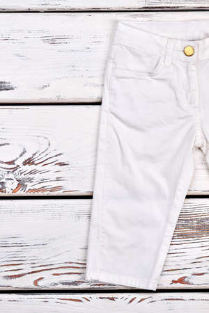 Kids white fashion trousers. Toddler boy white modern pants on wooden background, cropped image.の写真素材