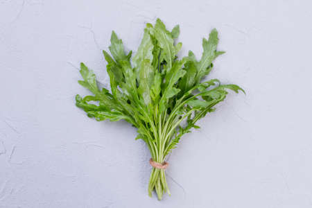 Bunch of arugula with brown twine. Fresh organic rucola on textured background. Tasty and nutritious plant.の写真素材