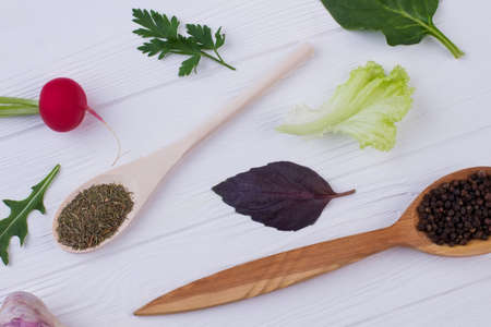Herbs and spices on white wood. Food cooking ingredients including arugula, radish, basil, lettuce and dry spices.の写真素材