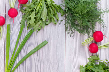 Fresh organic vegetables on wooden background. Fresh arugula, dill, onion, radish and parsley on gray wood, copy space. Choose right food.の写真素材