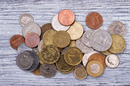 Pile of coins collection, top view. Wooden desk surface background.の写真素材