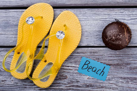 Flat lay, beach footwear and accessories. Top view, yellow flip flops with diamonds and casket,...