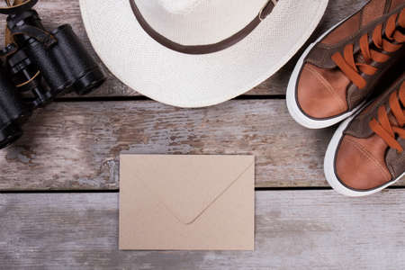 Post mail and travel accessories. Shoes, hat and binoculars. Wooden desk surface background.の写真素材