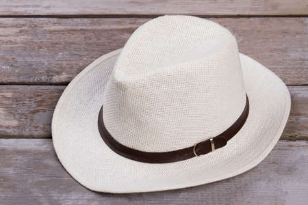 White straw hat close up. Wooden desk surface background.