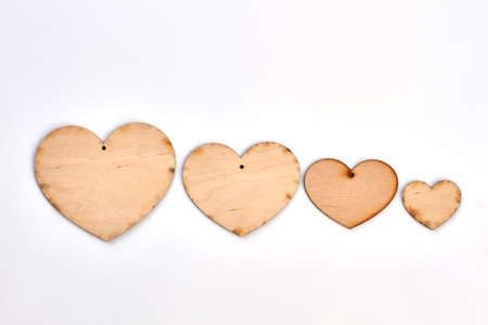 Row of wooden heart shaped cutouts. Four wooden hearts isolated on white background. Handmade decorations for Valentines Day.の写真素材