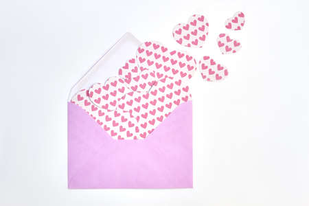 Background with a lot of paper hearts. Pink envelope with pink heart shaped figures cut from paper...