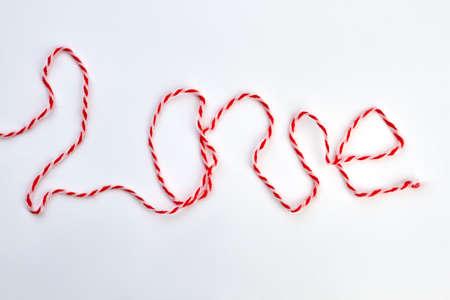 Word love from thread on white background. Inscription love from red and white woolen thread....