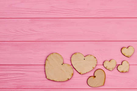 Set of plywood hearts and copy space. Brown rustic hearts made from wood on pink wooden background....