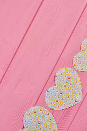 Wooden background with colorful paper hearts. Handmade paper hearts for banner on pink wood with copy space, top view. Valentines holiday concept.の写真素材
