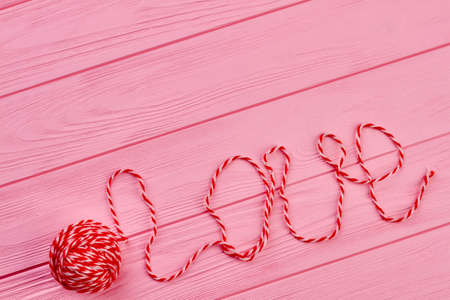 Inscription love written with threads for knitting. Red ball of yarn and copy space.の写真素材
