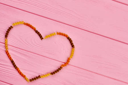 Valentines Day wooden background. Shape of heart from raw italian pasta and space for text.の写真素材