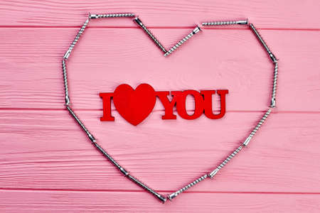 I love you inscription on pink wood. Shape of heart from framing nail on colorful wooden background. Happy Valentines Day.の写真素材