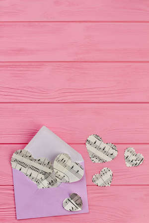 Envelope and paper hearts, top view. Opened envelope and hearts with music notes flying away, copy...
