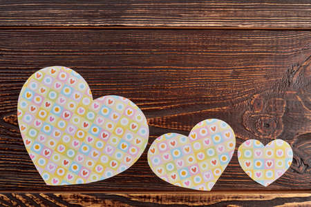 Paper hearts on brown wooden background. Row of paper hearts for banner with copy space on top.