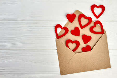 Happy Valentines Day wooden background. Valentines Day envelope and red paper hearts, copy space....
