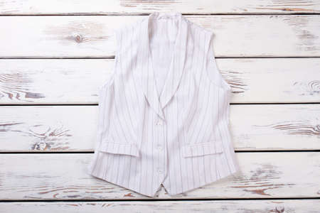Female white formal vest with black stripes. Women waistcoat on white wooden background. Ladies office outfit.の写真素材