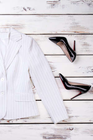 Women white blazer and black stilettos. Female elegant and fashion apparel on wooden background. Flat lay female styled look.の写真素材