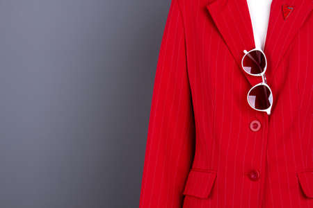 Women elegant blazer, sunglasses and copy space. Female mannequin in red fashion jacket, grey background. Feminine beauty and style.の写真素材