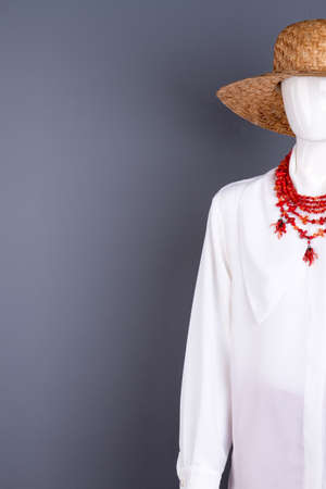 White blouse and red necklace, copy space. Female mannequin in straw hat, elegant blouse and jewelry, cropped image.の写真素材