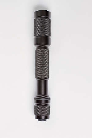 Black flashlight on white. Top view, flat lay.