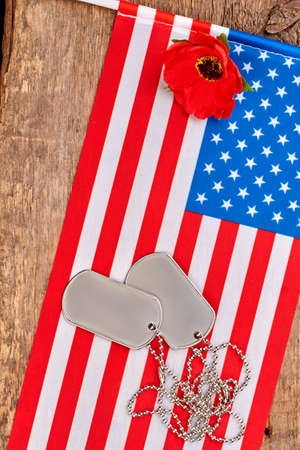 Dog tags, red poppy and american usa flag. Wooden desk bakground.の写真素材