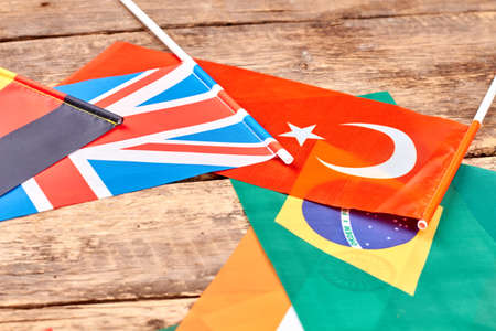 Different country flags on table. CLose up, flags on wood.