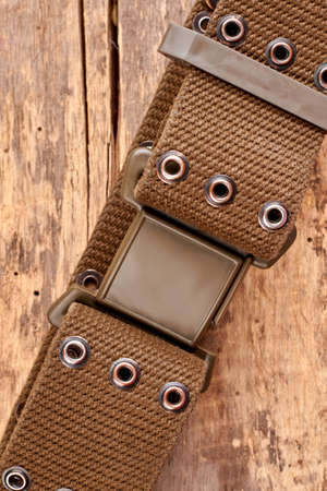 Close up military strap. Brown wooden desk background.の写真素材