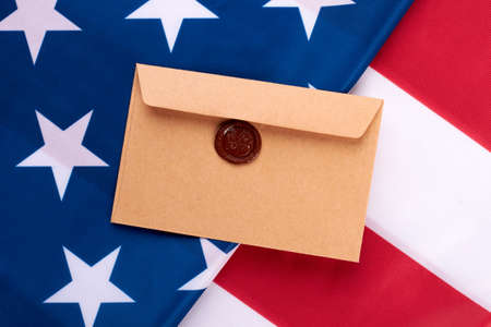 Brown envelope with stamp on American flag. American flag background with vintage style postal envelope. Greeting with National Day of USA.の写真素材
