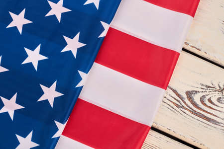 National flag of USA on white wood. Flag of United States of America folds on white wooden background. Symbol of USA.の写真素材