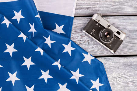 USA flag and film camera on grey wood. National flag of America and old-fashioned film camera on retro wooden background.の写真素材